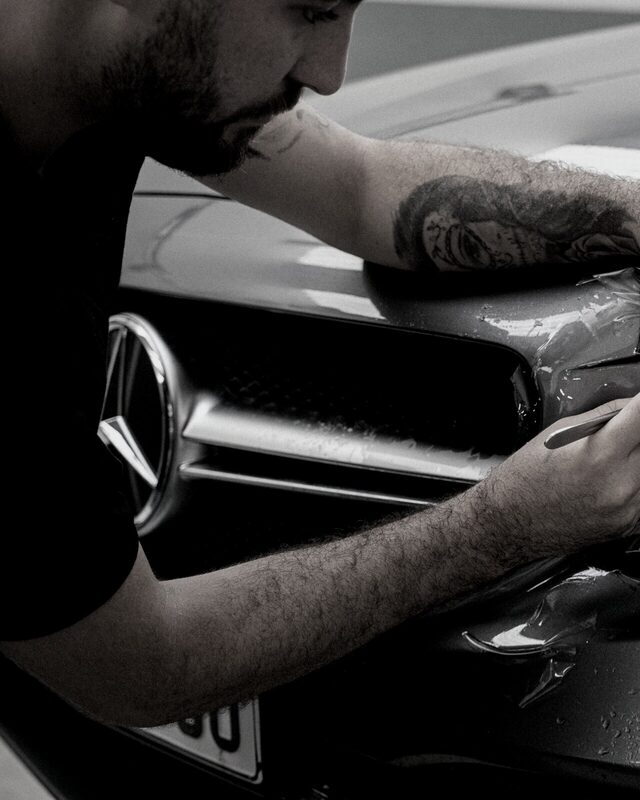 A Core Autobody technician refinishing a car body panel by hand in the East Vancouver shop